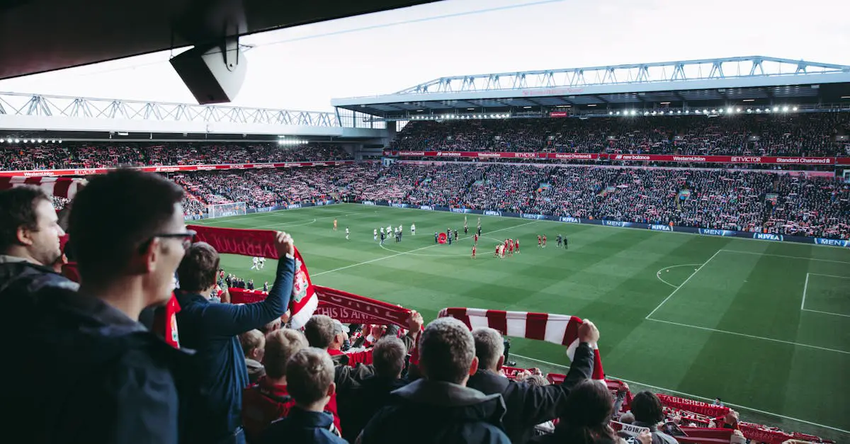 Crowd inside a large football stadium, with fans holding scarves and watching players on the field during a match.